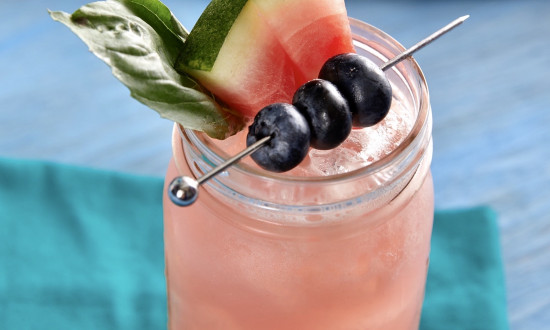 Watermelon Blueberry Basil Lemonade in mason jar with garnishes of basil, watermelon pieces and skewered blueberries
