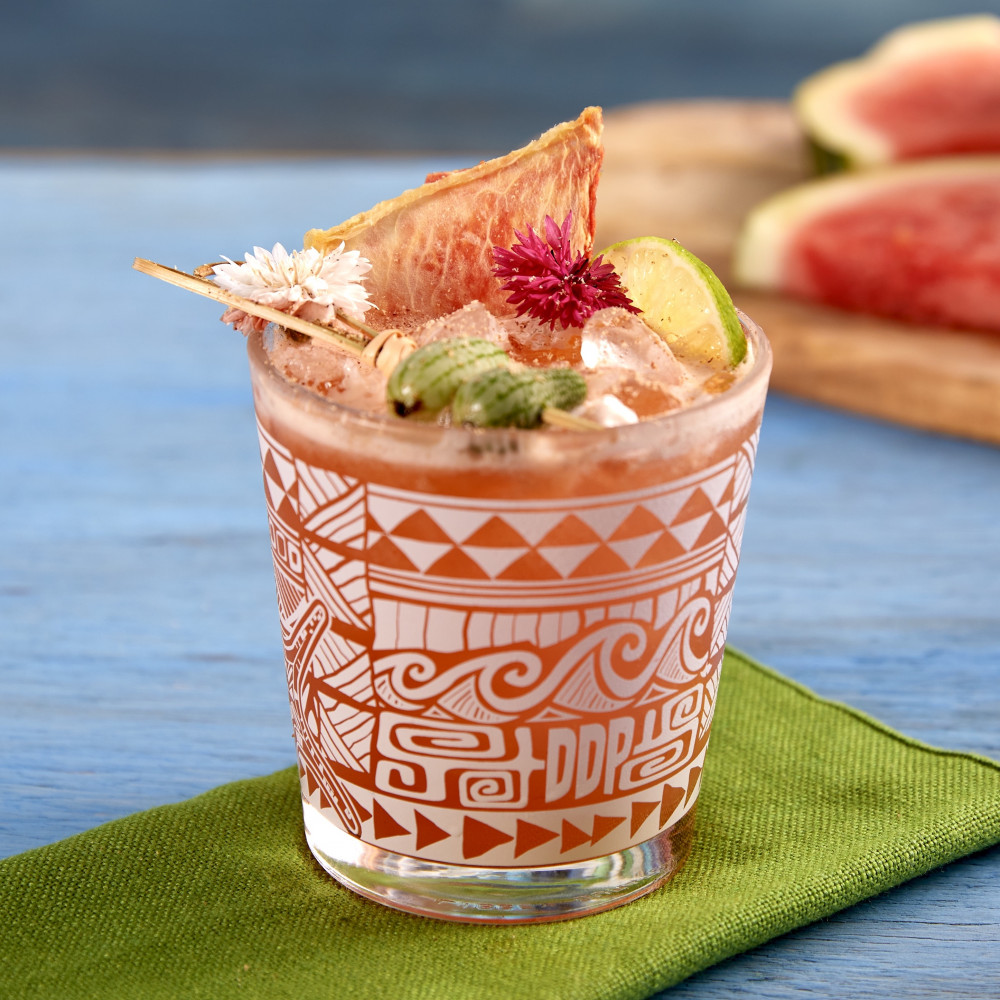 Watermelon Tiki Punch served in a low-ball glass garnished with lime wheel, flowers