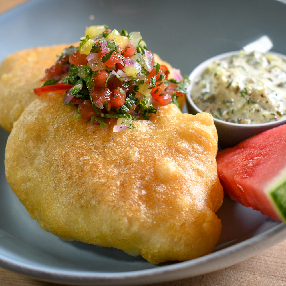 fried cod topped with chutney, tartar sauce on side with small wedge of watermelon