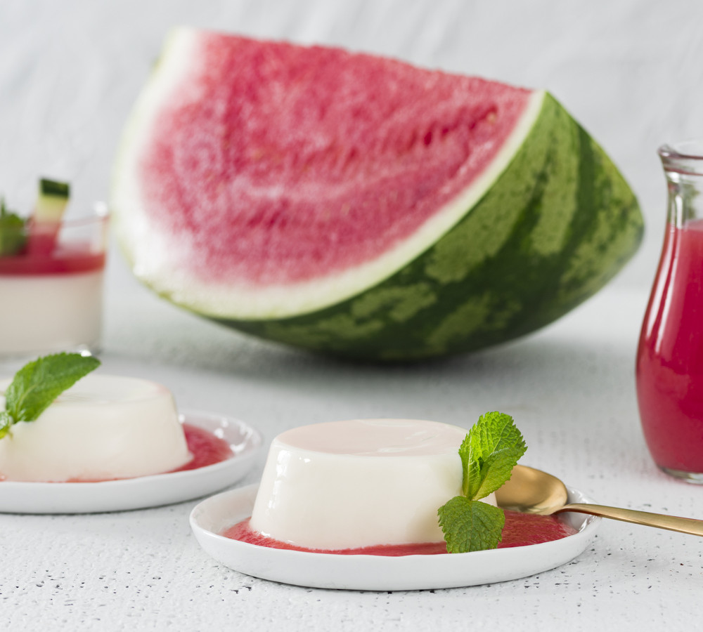 two dishes of watermelon panna cotta with syrup on the side