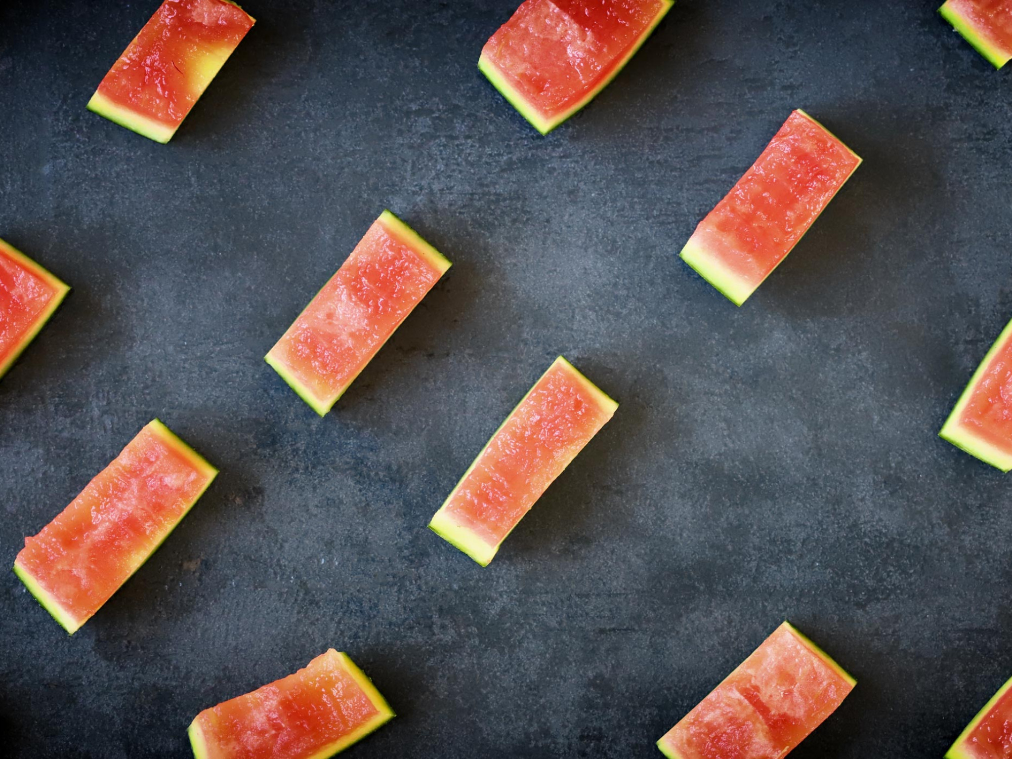 pieces of watermelon rind scattered on dark background