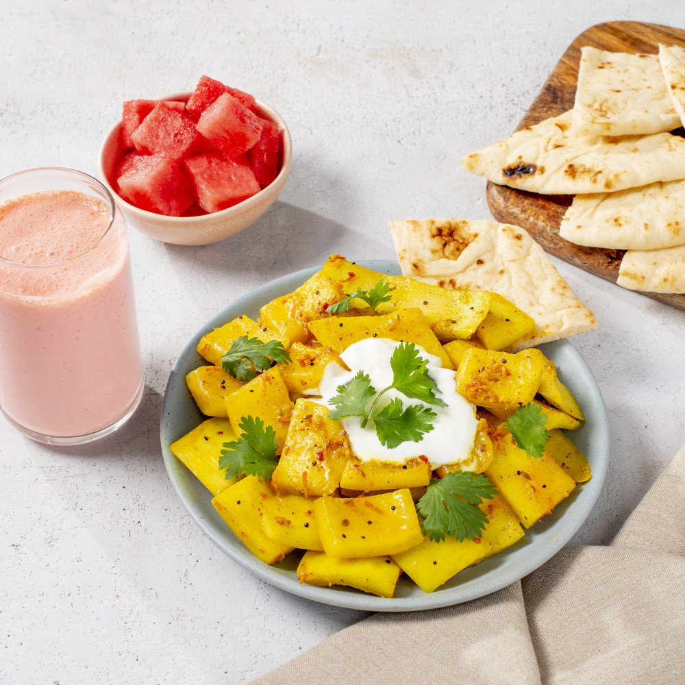 dish with garnished serving of recipe, naan, watermelon chunks and watermelon drink on side