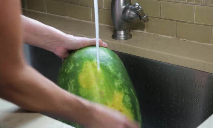 person washing a whole watermelon