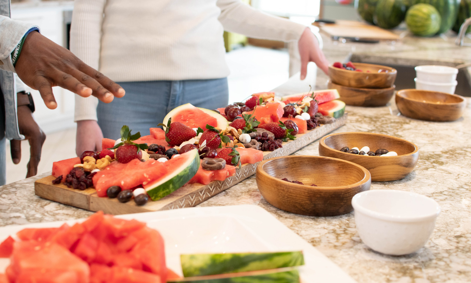 persons standing/arranging watermelon charcuterie board