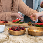 four people preparing watermelon charcuterie board