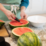the makings of watermelon serving shell/bowl with person in background