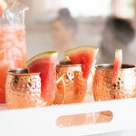 three mule mugs with watermelon garnish, alongside a pitcher of drink