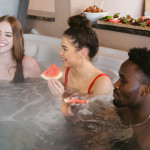 three people in hot tub with watermelon wedges with other watermelon dishes in background