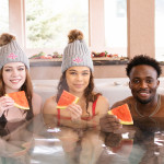3 people eating watermelon in a hot tub