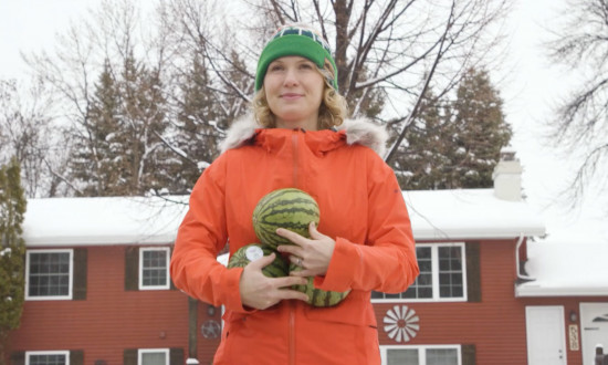 person holding 3 mini melons in front of a home, in snow