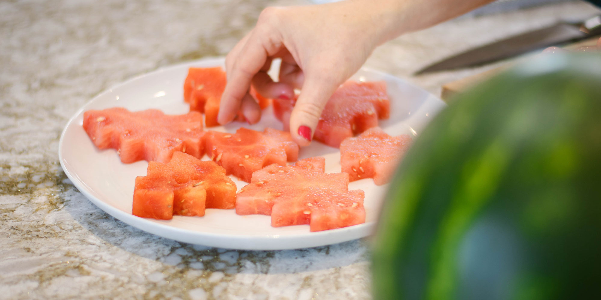 person arranging watermelon Christmas tree cutouts on platter