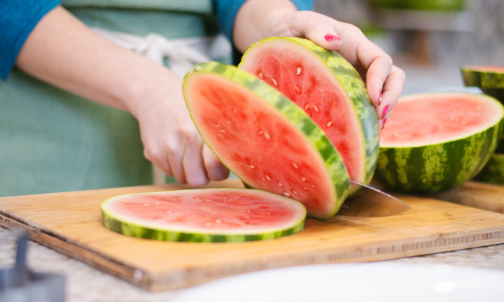 Close up of hands cutting watermelon into round slabs