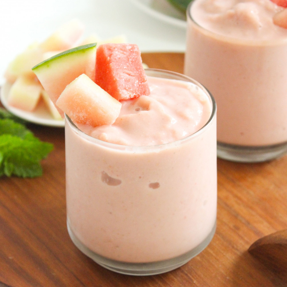Two watermelon rind smoothies on a board with fresh watermelon