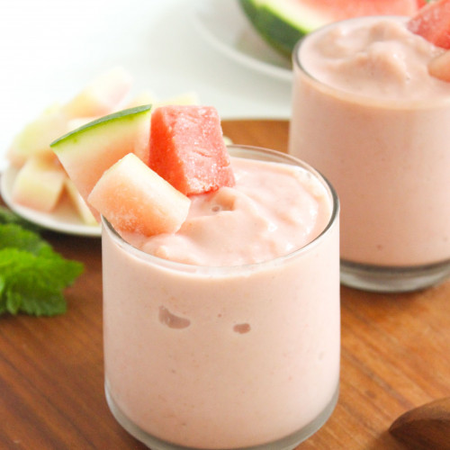 Two watermelon rind smoothies on a board with fresh watermelon