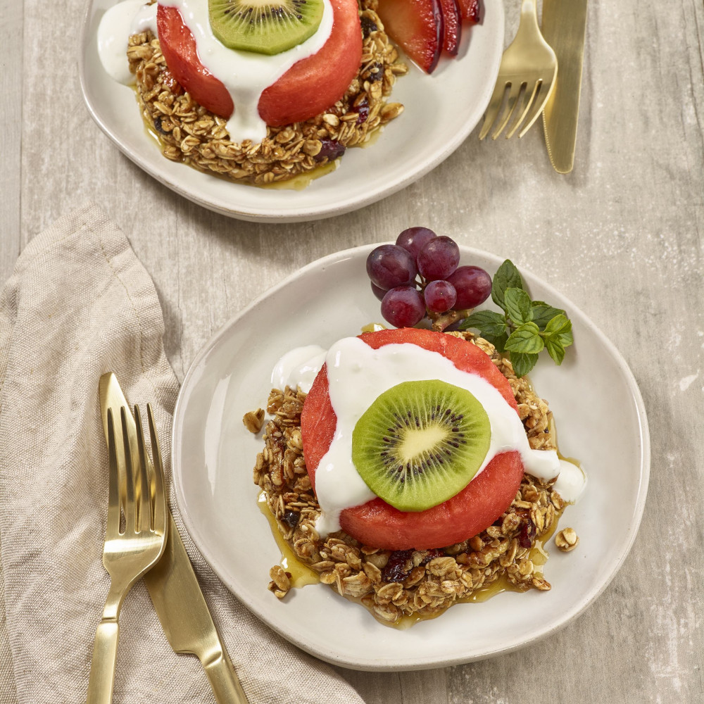 Two vegetarian watermelon and granola benedicts with utensils
