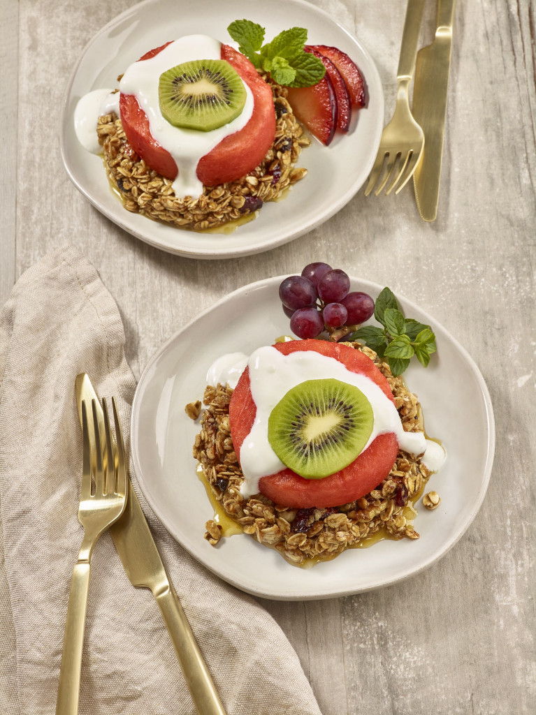 Two vegetarian watermelon and granola benedicts with utensils