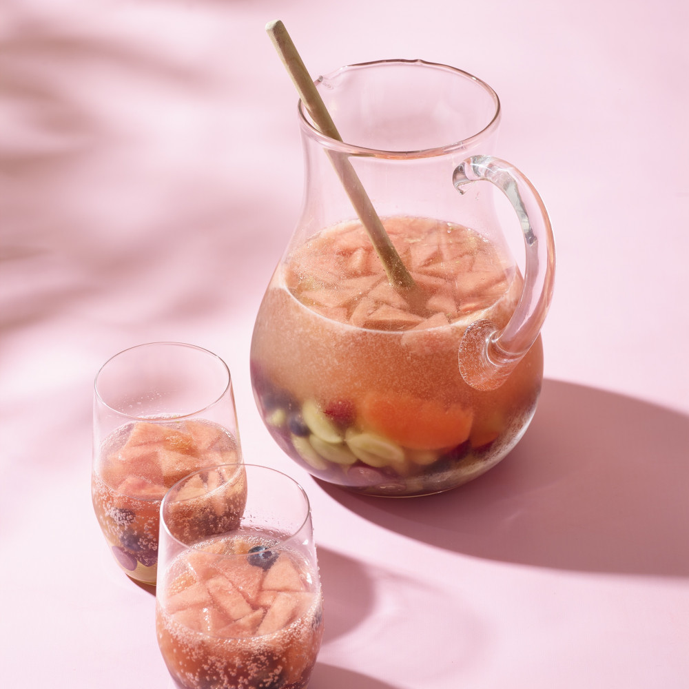 Watermelon champagne sangria in a pitcher with two glasses.