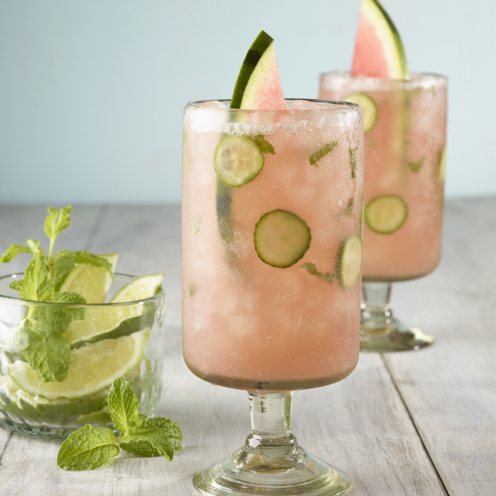 Two watermelon, cucumber and mint spritz beverages with watermelon spears.