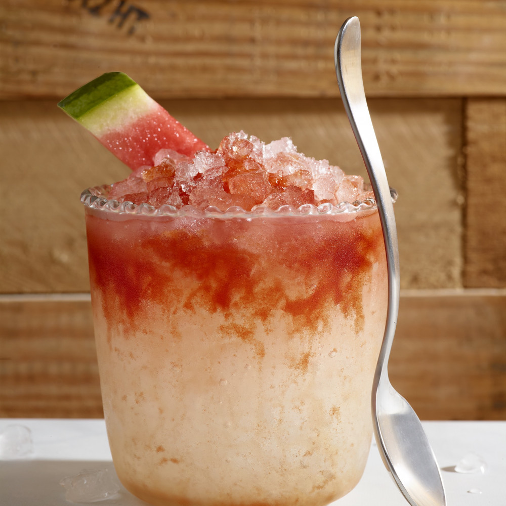 Watermelon syrup, ginger soda and ice in a glass with spoon.