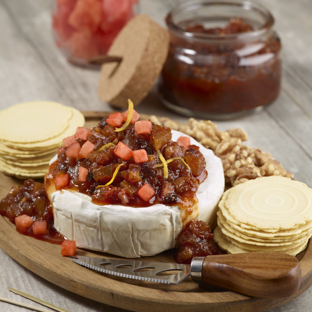 Chutney on top of brie with crackers on a serving board.