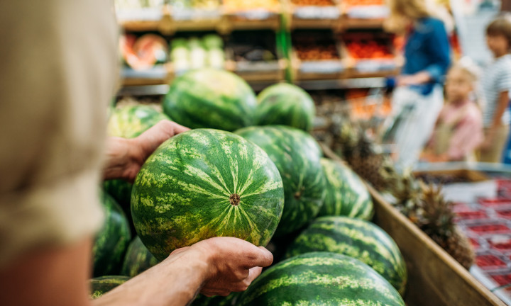 Melons in a grocery store being selected by close up of hands