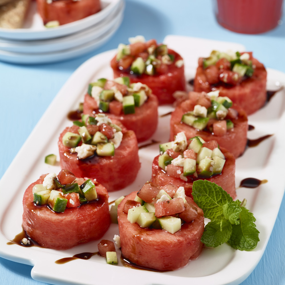 Watermelon cup appetizers with cucumber, mint, feta and drizzled balsamic on serving plate.