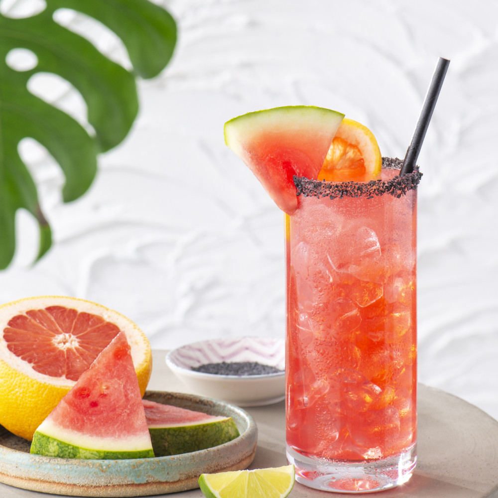 Paloma garnished with watermelon and grapefruit with garnish also on side plate