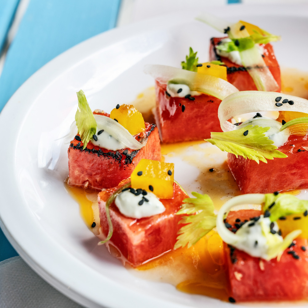 cubes of charred watermelon plated/salad with garnishes