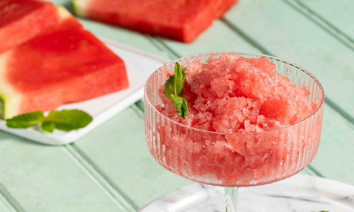 Two glasses of watermelon mint granita with watermelon wedges in the background.