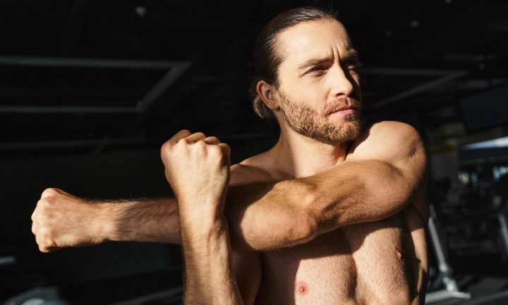 Muscular man stretching his triceps muscle