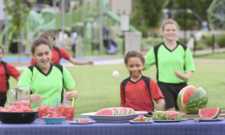Kids running to table with watermelon wedges and juice