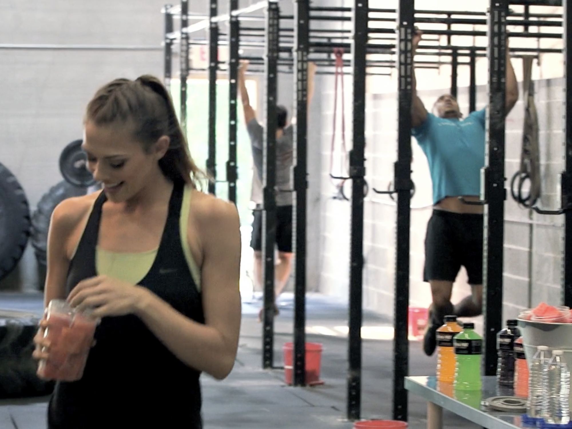 Woman surrounded by equipment in gym eating watermelon