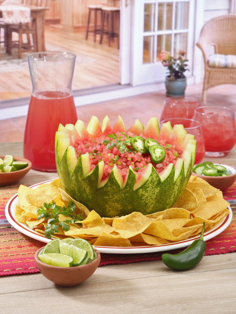 Half a watermelon filled with watermelon salsa and slices of jalapeño.
