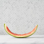 watermelon rind in shape of a smile in front of grey tile