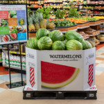 Watermelon bin filled with watermelons in the produce section of a grocery store.